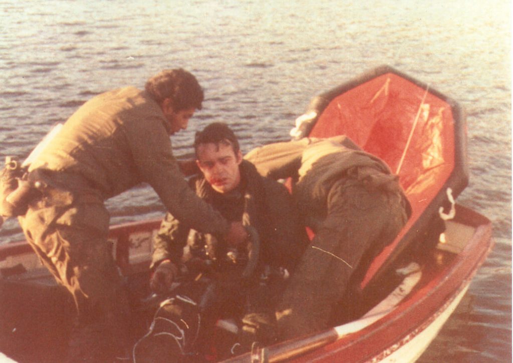 Un piloto es rescatado y detenido en un bote por dos soldados argentinos.