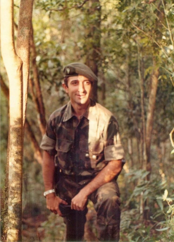 Soldado posa para una fotografía con un bosque en segundo plano.