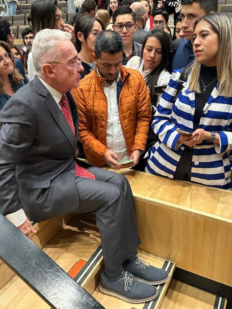 Presidente Álvaro Uribe reunido junto a estudiantes en un auditorio.